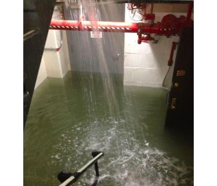 Water shooting out of pipe and causing flooding in stairwell.