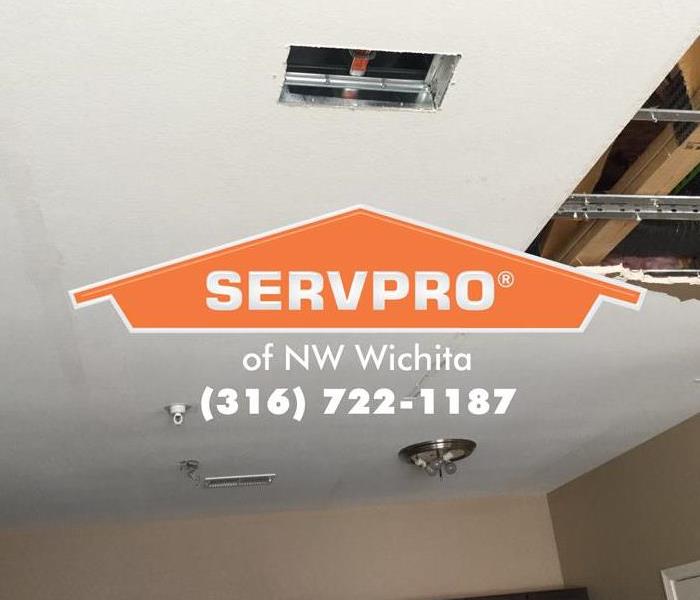 Big hole in ceiling and SERVPRO logo with phone number.
